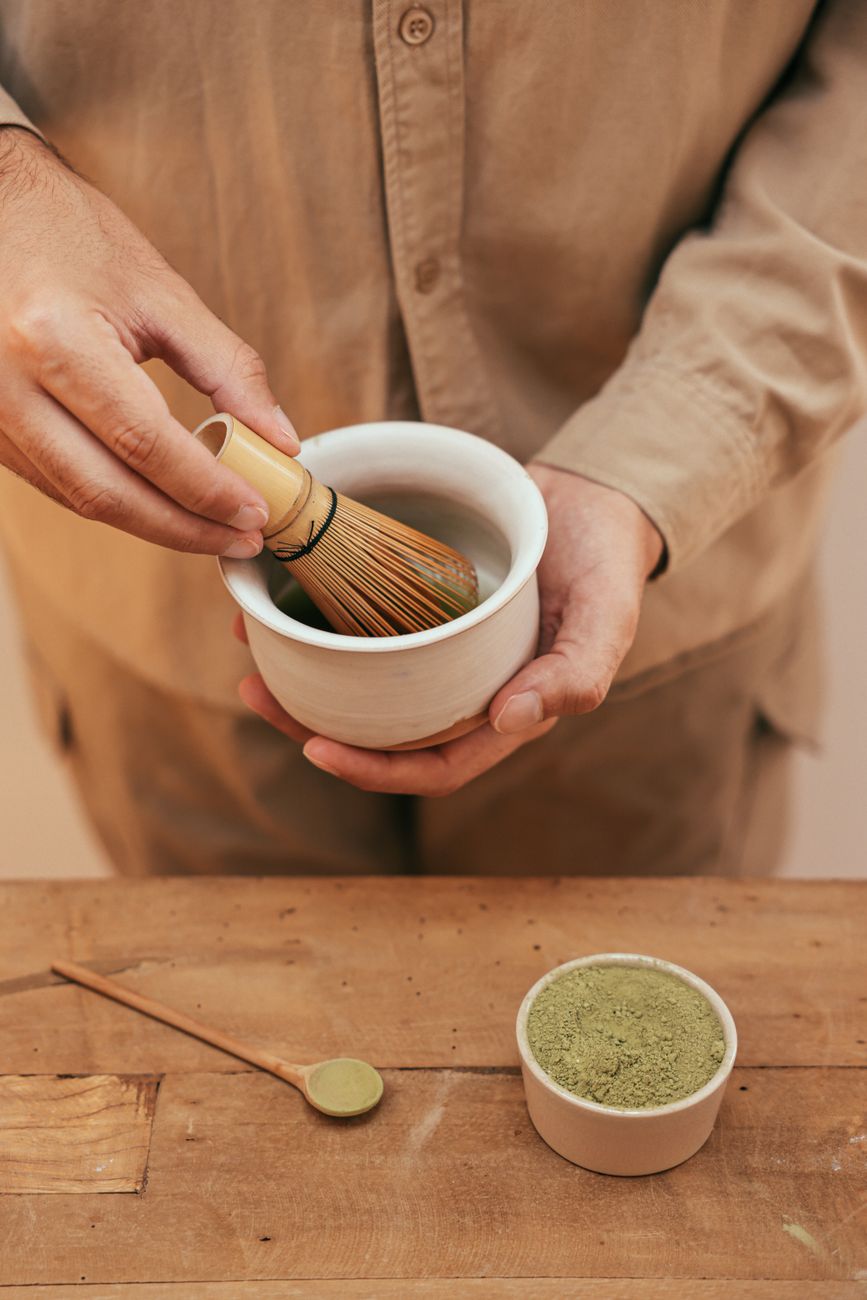 Hand preparing matcha green tea with bamboo whisk